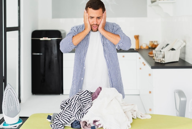 Foto hombre en estado de shock de toda la ropa para planchar