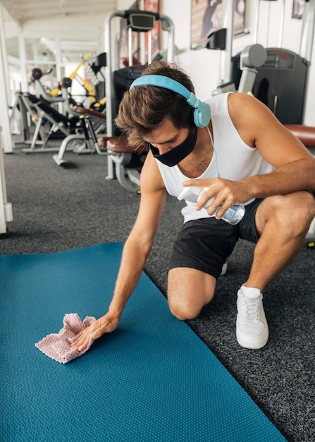 Foto hombre esterilla desinfectante en el gimnasio