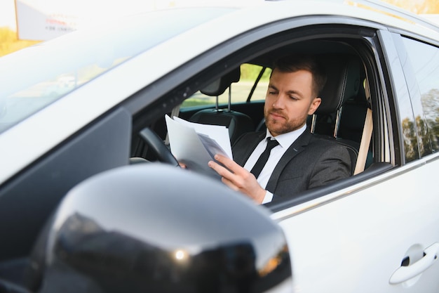 Hombre de estilo y estatus Apuesto joven en traje completo sonriendo mientras conduce un automóvil