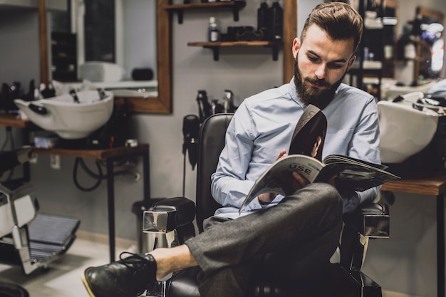 Hombre con estilo con revista en barbería