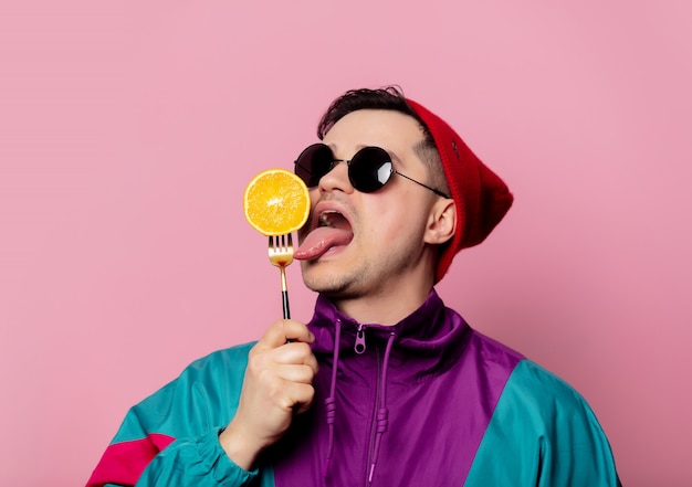 Hombre de estilo en vasos con naranja en un tenedor