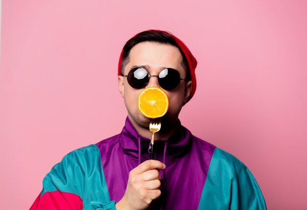 Hombre de estilo en vasos con naranja en un tenedor