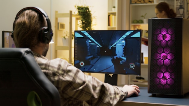 Foto hombre estirando antes de comenzar a jugar videojuegos en la computadora sentado en una silla de juego.