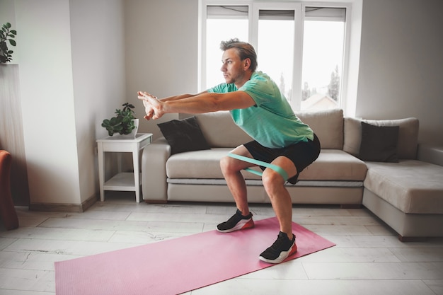 Hombre estirando y calentando en casa mientras hace fitness