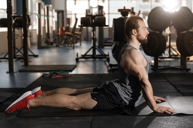 Hombre estirando la espalda después de entrenar en el gimnasio