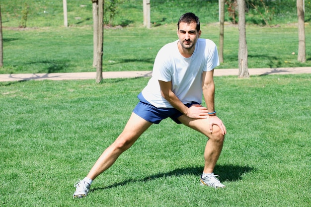 Hombre estirando los músculos en el parque de la ciudad