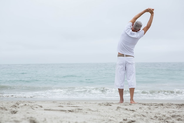 Hombre estirando sus brazos junto al mar