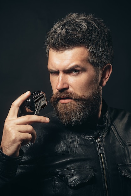 Hombre estrella de rock con barba larga cantante masculino con micrófono antiguo cantante barbudo concentrado