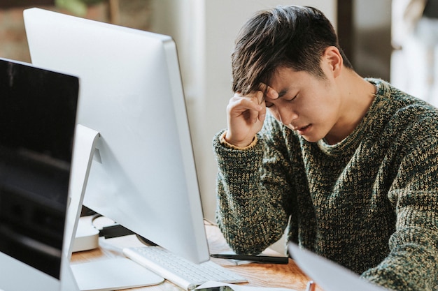 Hombre estresado y cansado sentado junto a una computadora