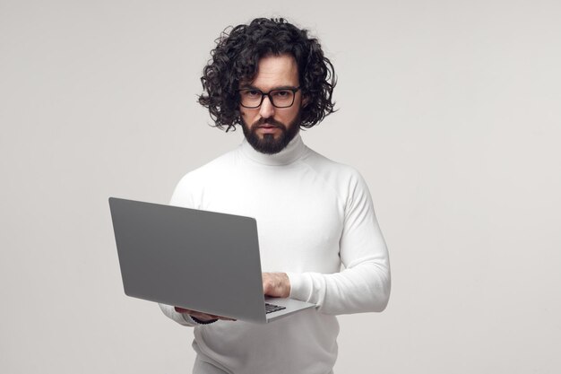 Foto hombre estricto en anteojos escribiendo en la computadora portátil en el estudio