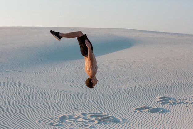 El hombre estudia parkour por su cuenta. Acrobacias en la arena