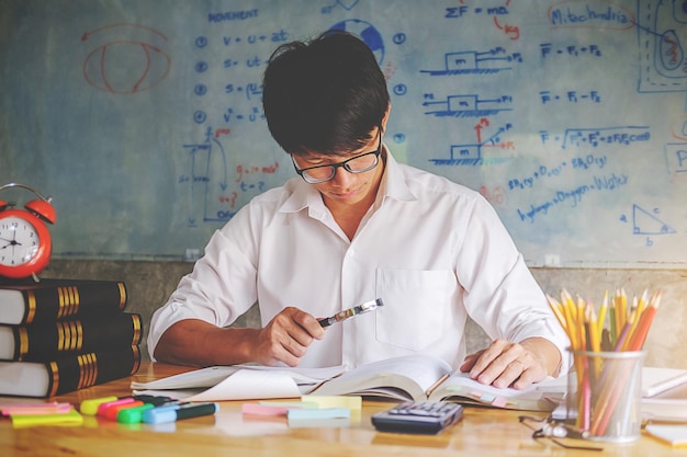 Hombre estudiando en el escritorio contra la pizarra