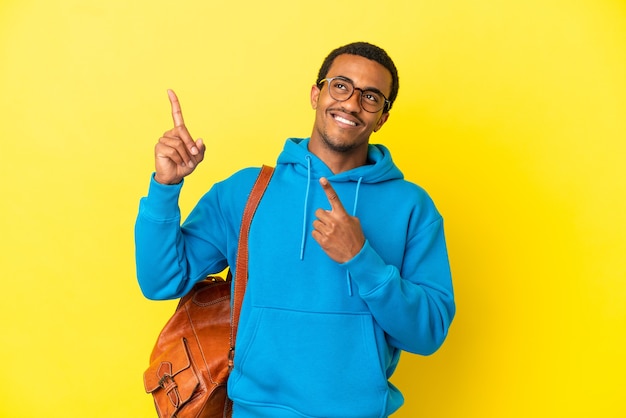 Hombre estudiante afroamericano sobre fondo amarillo aislado apuntando con el dedo índice una gran idea