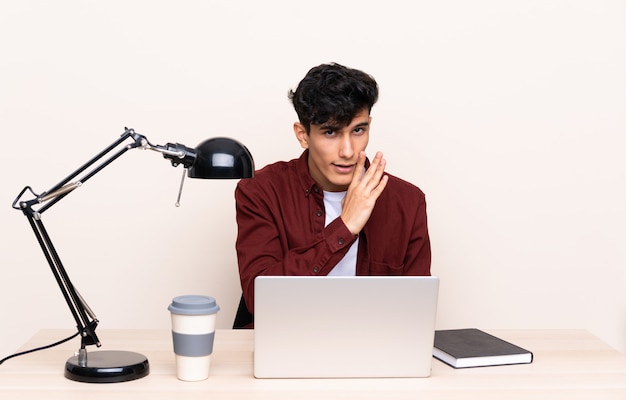 Hombre estudiante en un lugar de trabajo con una computadora portátil