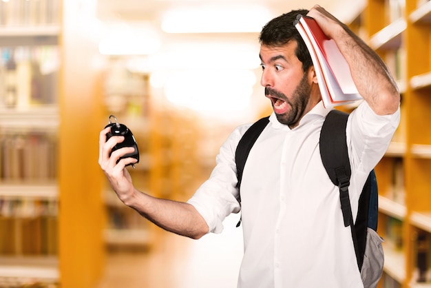 Hombre estudiante con reloj vintage en la biblioteca defocused