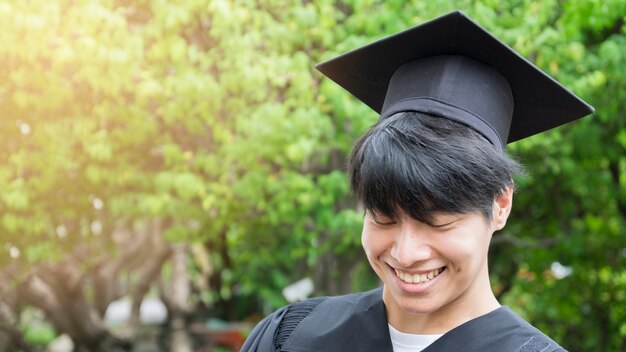 hombre estudiante sonríe y se siente feliz en vestidos de graduación y gorra