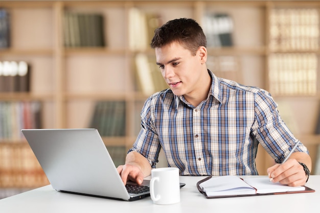 Hombre estudiante sonriente con laptop y café