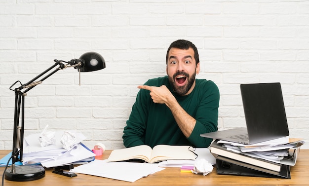 Hombre estudiante sorprendido y apuntando con el dedo al lado