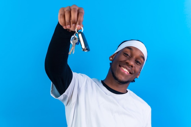 Hombre étnico negro vestido de blanco sobre un fondo azul nuevo concepto de llaves de casa