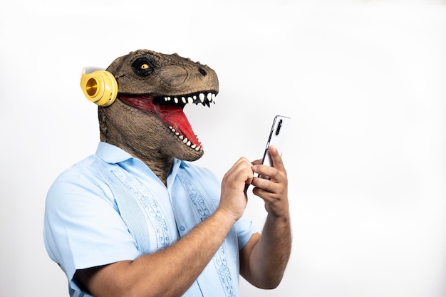 Hombre eufórico con cabeza Trex con teléfono inteligente sobre fondo blanco Concepto de enmascaramiento surrealista