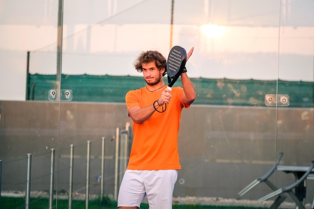 Foto hombre evaluando con una raqueta de tenis