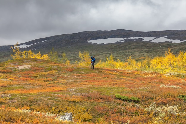 Hombre excursionista mochila en Kungsleden trail admirando la naturaleza de Sarek en Suecia Laponia con montañas