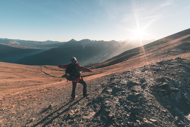 Hombre excursionista relajante al atardecer en la cima de la montaña y mirando el majestuoso panorama de los Alpes italianos