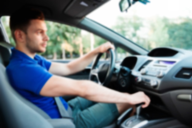 Hombre de éxito guapo está conduciendo su coche moderno en borrosa