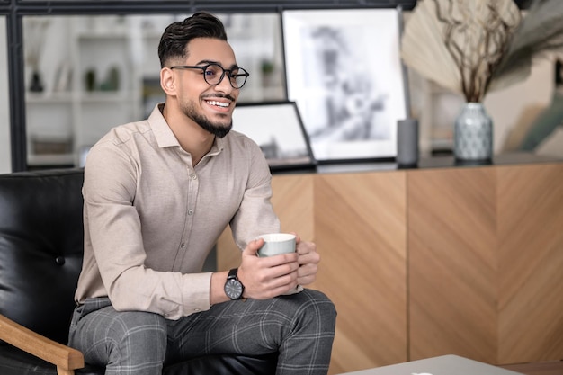 Hombre exitoso con café sentado sonriendo