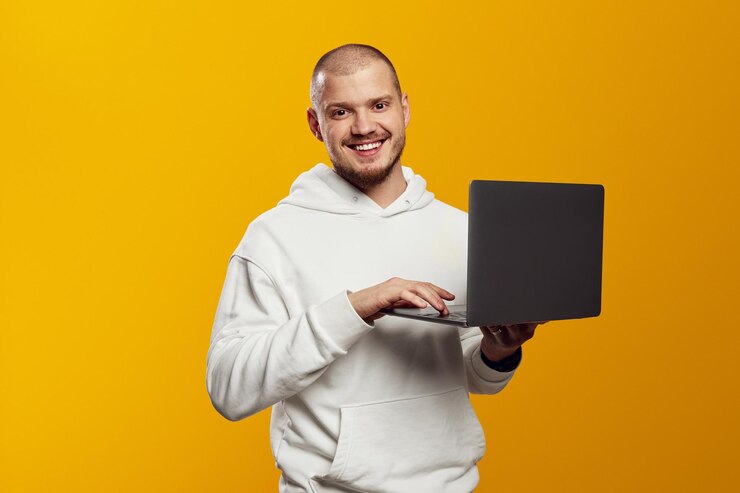 Hombre exitoso estudiante independiente usando una computadora portátil que trabaja de forma remota aislado sobre fondo amarillo