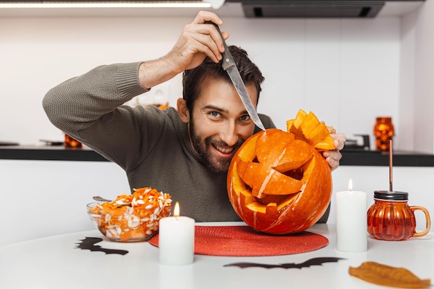 Un hombre expresivo preparando una calabaza para Halloween