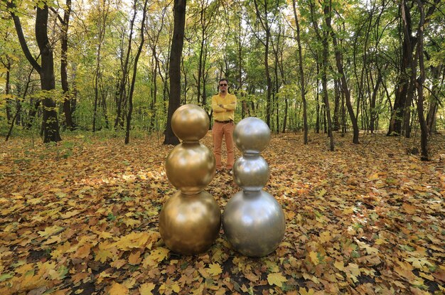 hombre con una extraña cabeza de bola dorada en el bosque