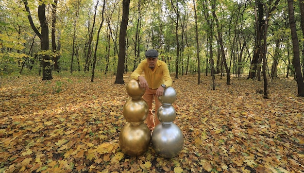 hombre con una extraña cabeza de bola dorada en el bosque