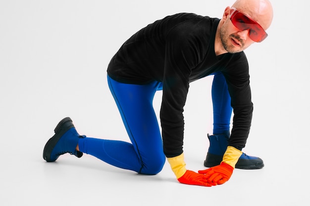 Hombre extraño en guantes de goma amarillo rojo en gafas futuristas y medias con posando en estudio blanco