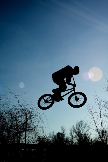 Foto el hombre extremo está saltando en una bicicleta sobre un fondo de cielo oscuro.