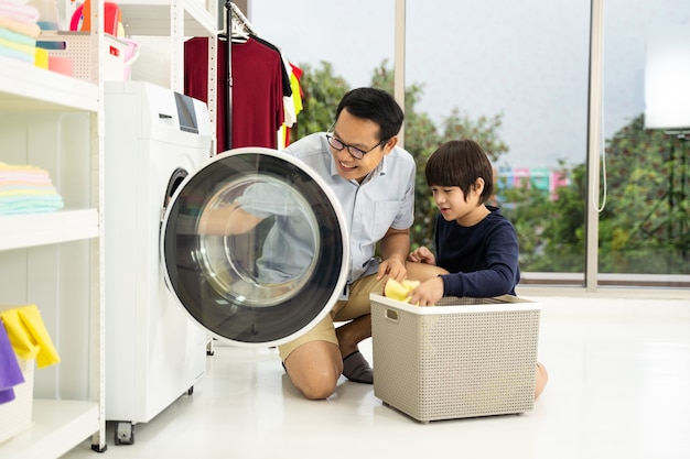 Hombre de familia feliz padre cabeza de familia e hijo pequeño ayudante se divierten y sonríen mientras lavan la ropa con la lavadora