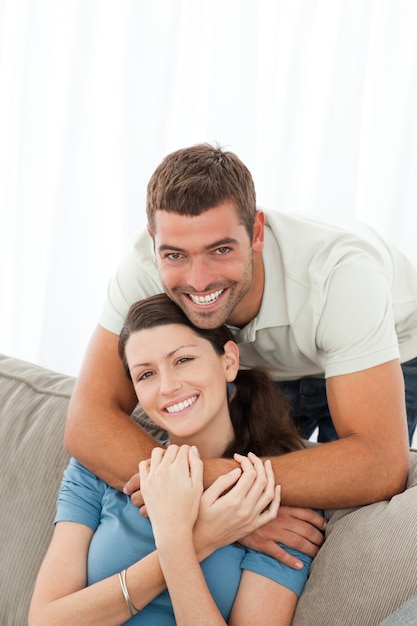 Hombre feliz abrazando a su novia sentada en el sofá