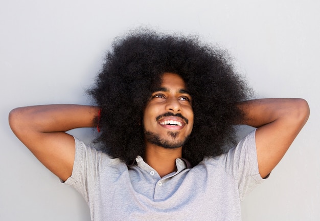 Hombre feliz con afro mirando relajado con las manos en el pelo