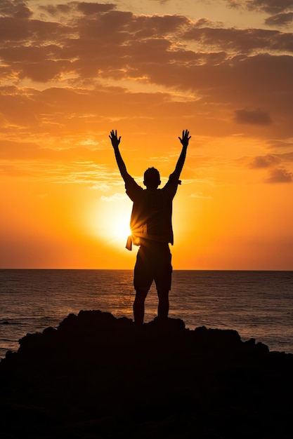 un hombre feliz agitando sus manos en el aire contra la puesta de sol