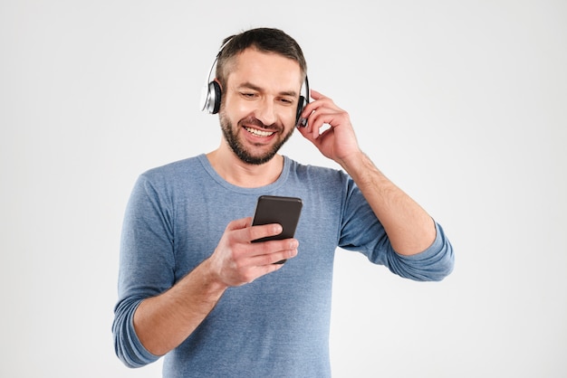 Hombre feliz aislado música mediante teléfono móvil.