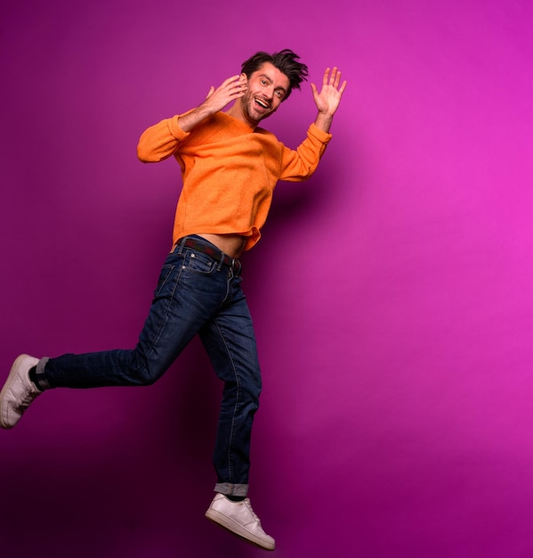 El hombre feliz y alegre salta contra un fondo morado