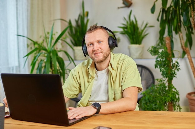 Hombre feliz con auriculares inalámbricos mira el curso de capacitación del seminario web