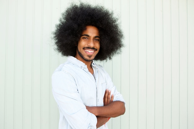 Hombre feliz con barba y afro de pie con los brazos cruzados