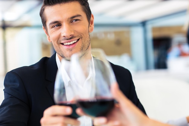 Hombre feliz bebiendo vino en el restaurante