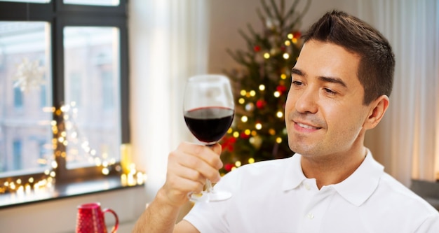 hombre feliz bebiendo vino rojo en casa en Navidad
