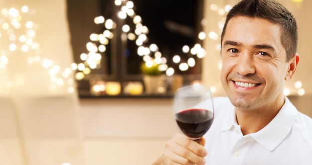 hombre feliz bebiendo vino rojo en casa en Navidad