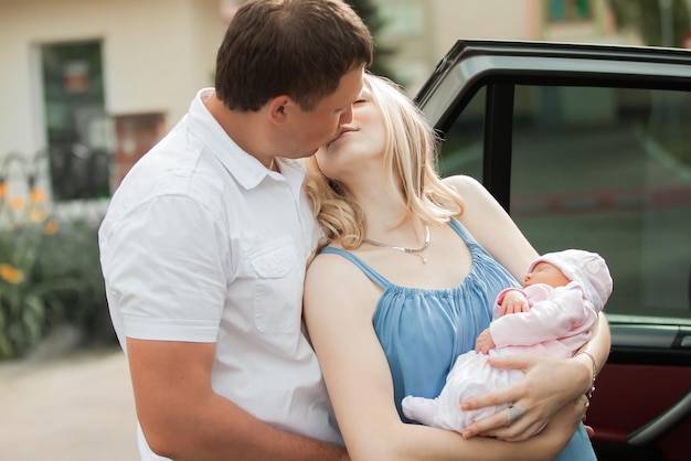 Hombre feliz besando a su esposa con un bebé recién nacido. el concepto de felicidad familiar