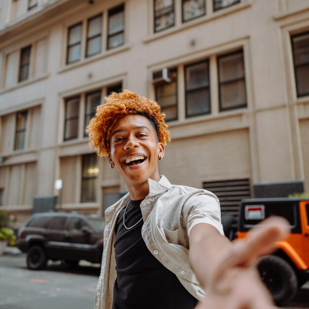 Foto un hombre feliz de cabello rojo está sonriendo y apuntando a la cámara mientras está de pie frente a un vehículo