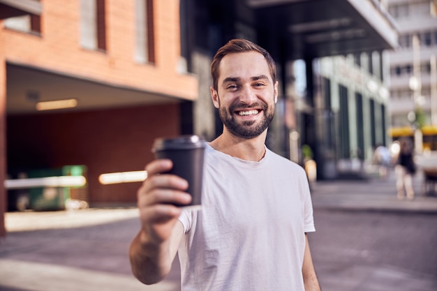 Hombre feliz con café sonrisas al aire libre de cerca