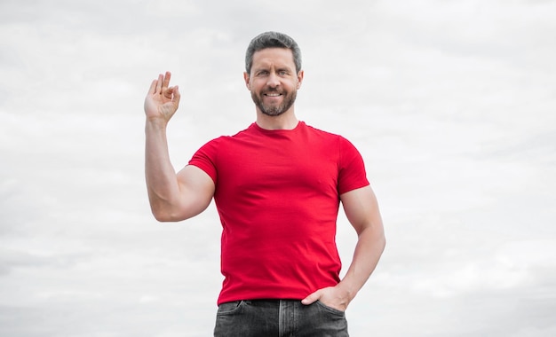 Hombre feliz con camisa roja al aire libre en el fondo del cielo ok